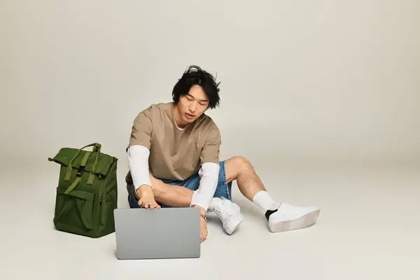 Stylish young man interacts with laptop on the floor, exuding modern urban fashion vibes. — Stock Photo
