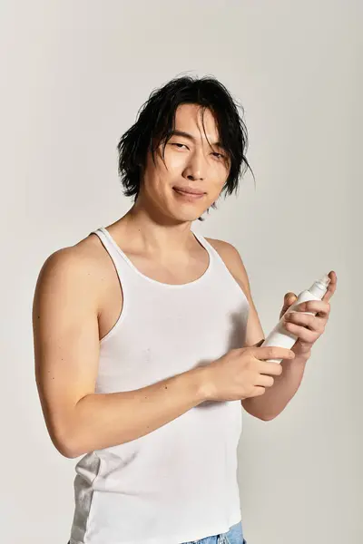 Stylish young man holds a skincare product, exuding confidence and embracing modern fashion trends. — Stock Photo