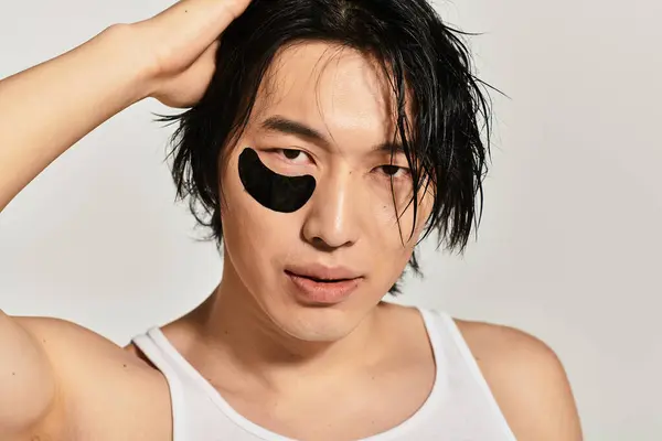 Young man with a fashionable look emphasizes skincare while posing confidently in a modern space. — Stock Photo