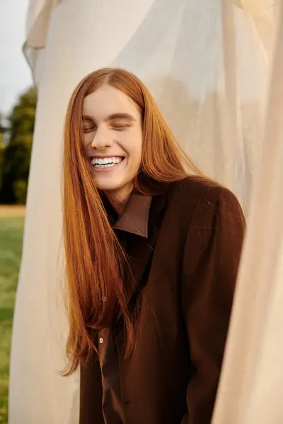 Charming young man in stylish attire smiles brightly, embodying confidence in a natural backdrop. — Stock Photo