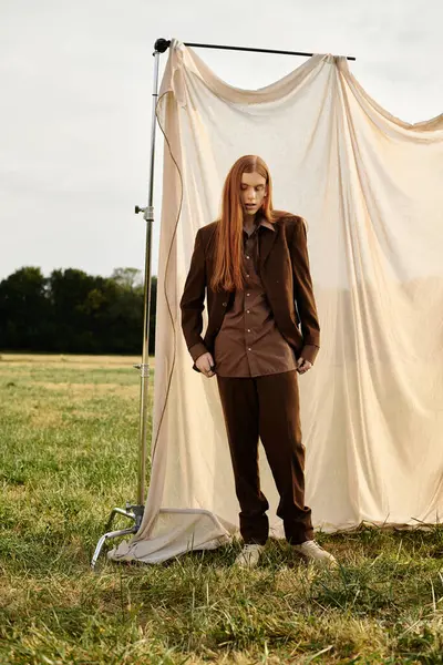Striking young man with long hair presents modern fashion against a serene nature backdrop. — Stock Photo