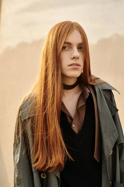 A young handsome man with long hair stands confidently, exuding fashion and elegance. — Stock Photo