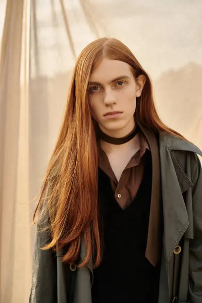 A young man with long hair showcases his style in a natural environment during golden hour. — Stock Photo
