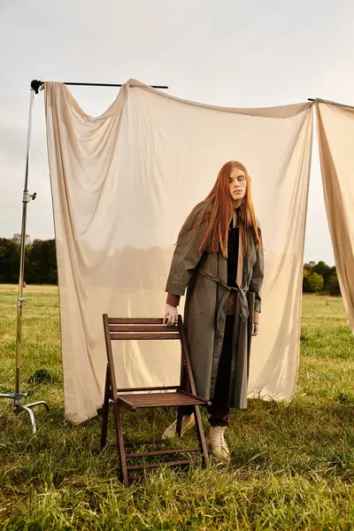 A young man with long hair showcases trendy fashion while standing on a grassy field. — Stock Photo