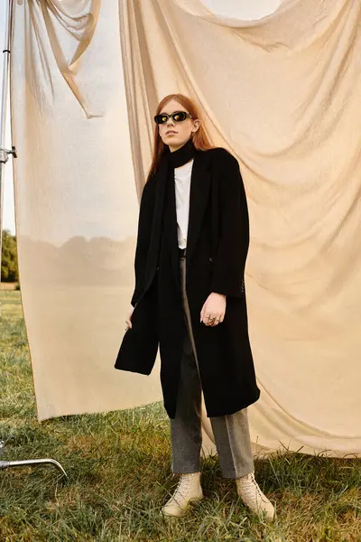 A stylish individual confidently poses in fashionable attire on a grassy field. — Stock Photo