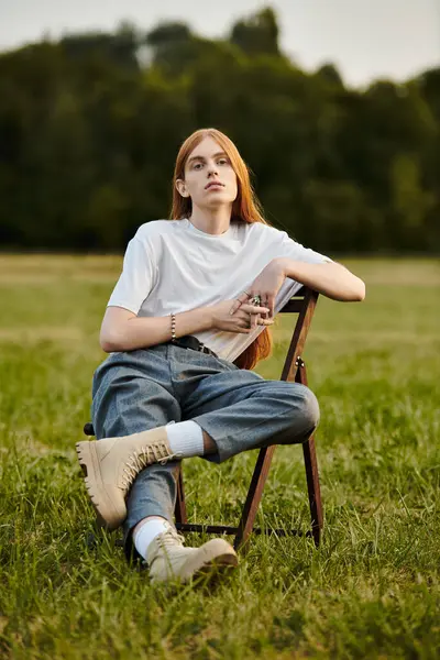 A young man in trendy attire relaxes outdoors, enjoying the beauty of nature. — Stock Photo