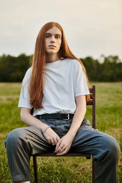 Confident young man sits in a green field, showing off his style and charm. — Stock Photo