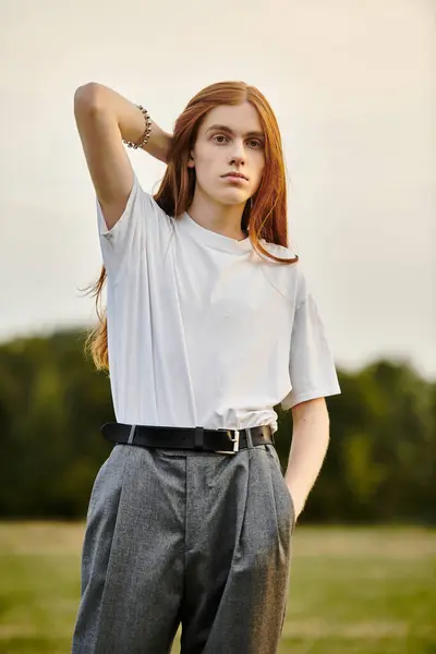 A young man stands confidently in a stylish outfit, surrounded by nature as the sun sets. — Stock Photo
