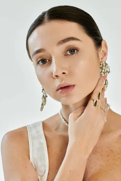 Stylish young woman highlights her exquisite jewelry while striking an elegant pose indoors. — Stock Photo