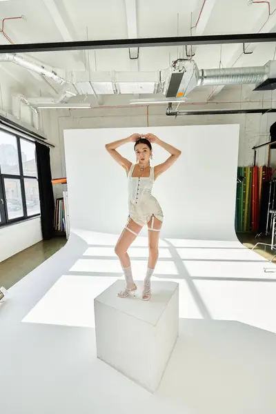 A young gymnast poses elegantly on a pedestal in a bright studio. — Stock Photo