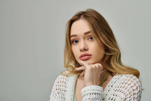 A young pretty woman poses thoughtfully, displaying her stylish attire in a soft, light setting. — Stock Photo