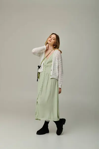 A young woman with a stylish spring outfit elegantly poses with grace in a softly lit environment. — Stock Photo