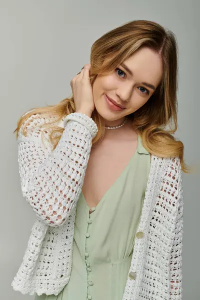 Giovane donna vestita con un abito accogliente abbraccia le vibrazioni primaverili con un sorriso giocoso. — Foto stock