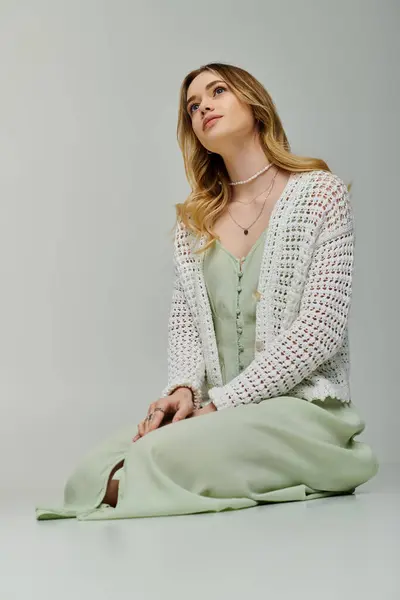 A stylish young woman sits gracefully in a trendy green outfit, exuding spring elegance. — Stock Photo