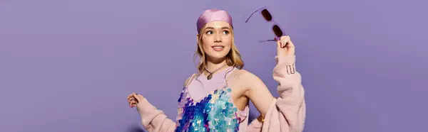 A young woman joyfully poses in trendy attire with sunglasses against a pastel background. — Stock Photo