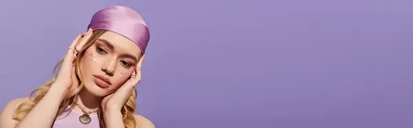 A young woman poses in a stylish outfit against a soft purple backdrop, radiating beauty. — Stock Photo