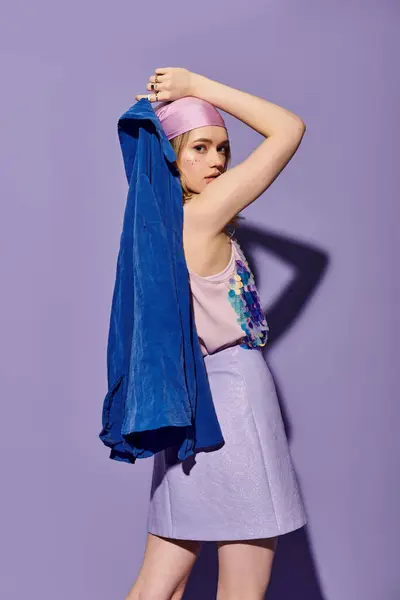 Eine junge Frau zeigt selbstbewusst ihr modisches Outfit, während sie ein blaues Kleidungsstück in der Hand hält. — Stockfoto