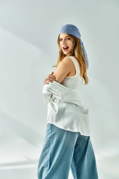 A fashionable young woman models her spring outfit in a trendy studio with a grey backdrop. — Stock Photo