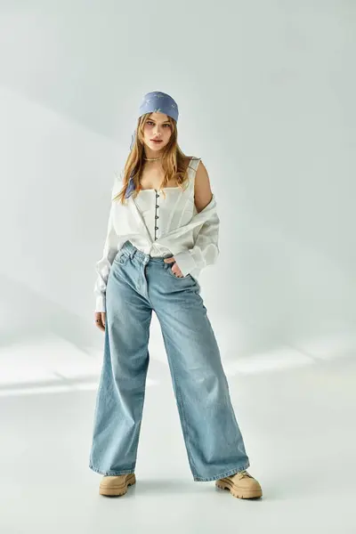 A stylish young woman poses confidently in spring fashion against a grey backdrop. — Stock Photo