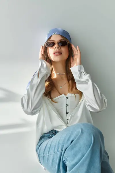 Una mujer joven y chic modela un atuendo de moda en un elegante estudio gris. — Stock Photo