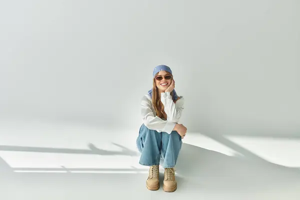 A young woman models a trendy spring outfit in a bright studio with a grey backdrop. — Stock Photo