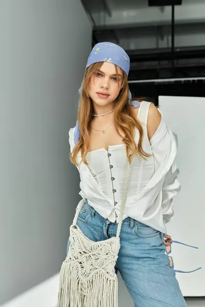 A young woman displays her stylish spring outfit against a grey backdrop, exuding energy. — Stock Photo