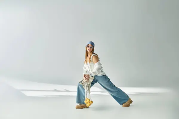 Une jeune femme élégante pose dans une tenue de printemps tendance sur un fond gris doux. — Photo de stock