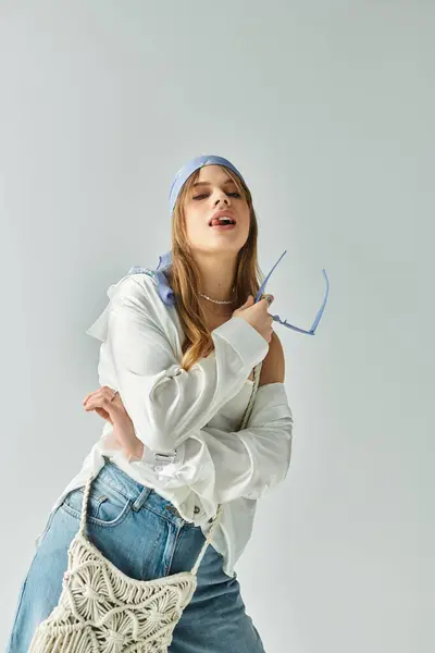 A young woman expresses spring vibes in her trendy outfit within a minimalist studio backdrop. — Stock Photo