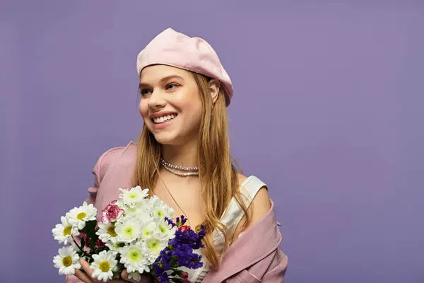 Una joven mujer irradia alegría con un atuendo de primavera, sosteniendo flores vibrantes en un elegante ambiente de estudio. - foto de stock