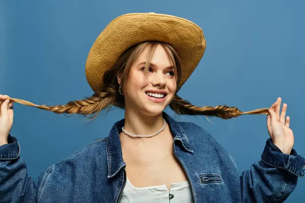 Una joven alegre con una chaqueta de mezclilla posa sobre un fondo azul brillante de primavera. — Stock Photo