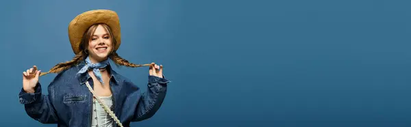 A young woman embraces spring in a stylish denim jacket against a blue backdrop, radiating joy. — Stock Photo