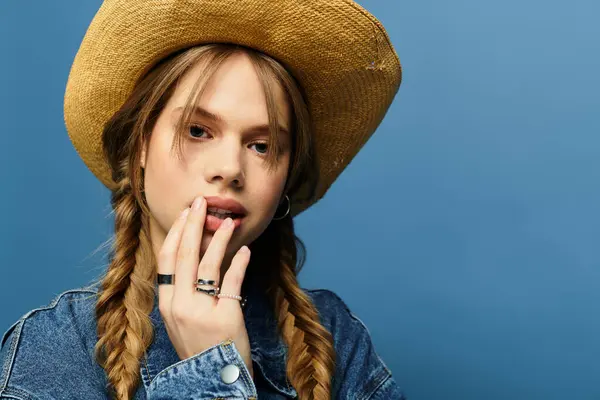 A young woman poses playfully in a stylish denim jacket in a spring-themed studio. — Stock Photo