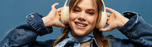 Bright and cheerful young woman in a denim jacket smiles while listening to music in a studio, banner — Stock Photo