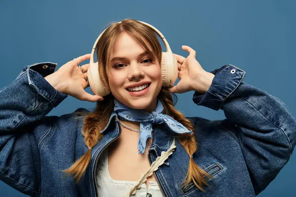 A young woman wears a denim jacket and headphones while showcasing a cheerful spring mood. — Stock Photo
