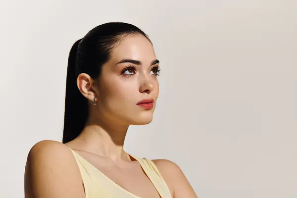 A confident young woman stands gracefully, looking up with a determined expression in soft light. — Stock Photo