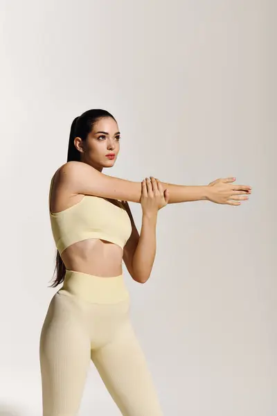 A young, sporty woman stretches gracefully in a bright studio, exuding athletic elegance. — Stock Photo