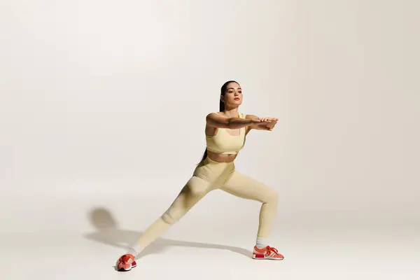 Joven hermosa mujer realiza una sentadilla atlética, exudando confianza y determinación en un estudio. — Stock Photo