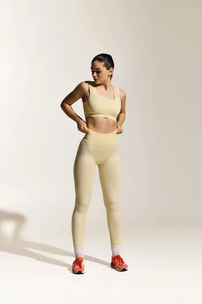 Young beautiful woman adjusts her sporty outfit while exuding confidence and energy in motion. — Stock Photo