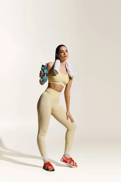 Athletic woman holds a water bottle, exuding confidence and sporty style. — Stock Photo
