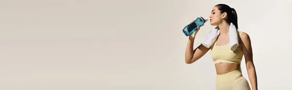 A fit young woman takes a refreshing water break after a workout in a stylish gym. — Stock Photo