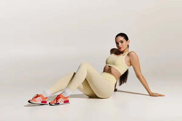 Eine junge schöne Frau zeigt ihren athletischen Geist, während sie stilvoll in sportlicher Kleidung sitzt. — Stockfoto