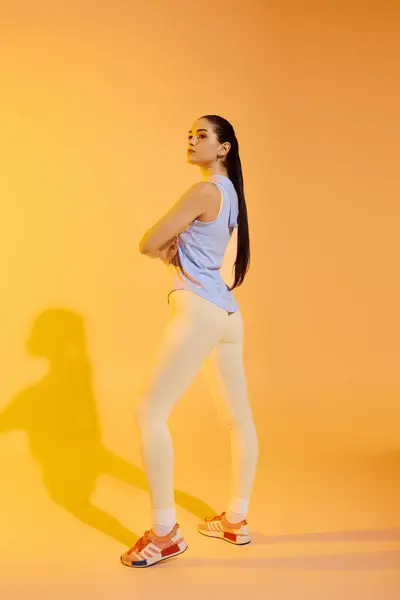 A young beautiful woman displays her sporty attire while confidently posing in a vibrant setting. — Stock Photo