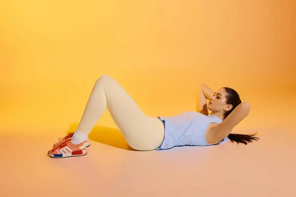 A young woman does crunches against a vibrant pastel background, embracing fitness. — Stock Photo