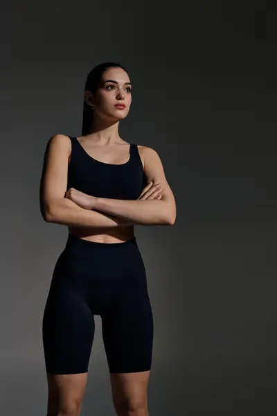 A confident young woman stands tall with arms crossed, exuding athleticism and style. — Stock Photo