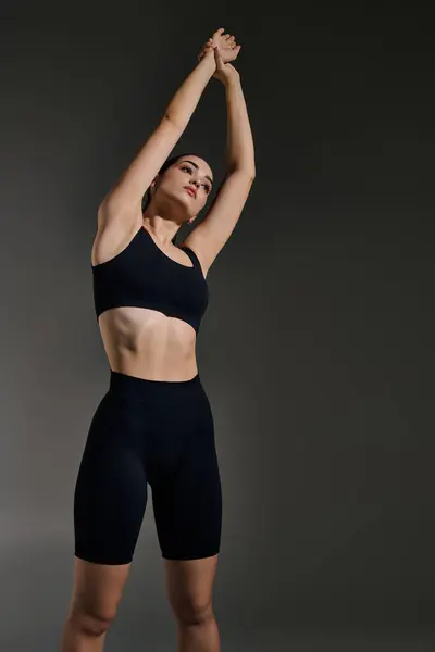 Una joven hermosa mujer realiza un estiramiento elegante, mostrando su forma atlética y enfoque. - foto de stock