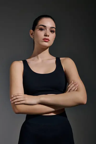 Confident youthful woman stands with arms crossed, showcasing her athletic build and beauty. — Stock Photo