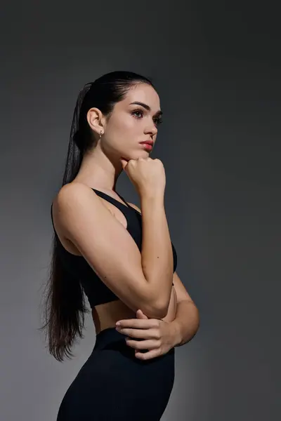 A young, sporty woman poses confidently with her hand on her chin, exuding elegance. — Stock Photo