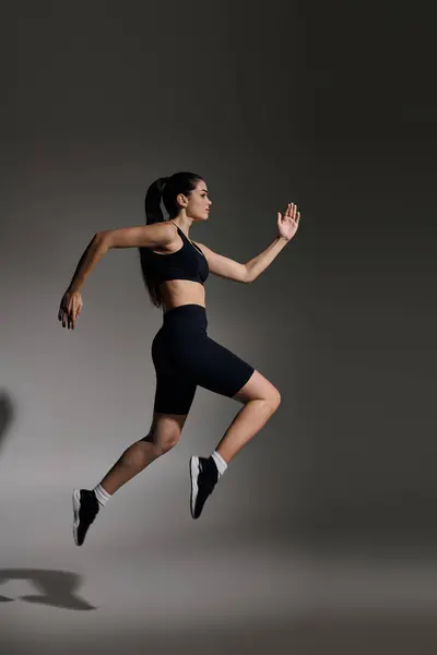 A focused young woman runs purposefully, showcasing her athleticism in a vibrant scene. — Stock Photo