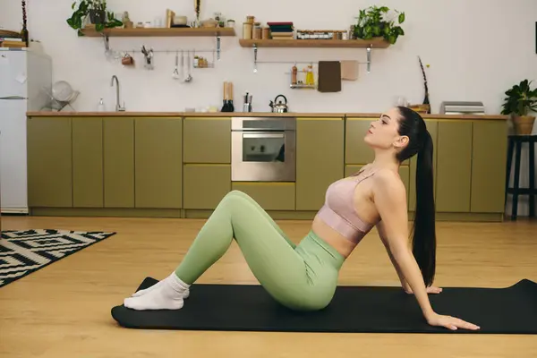 Mujer joven dedicada se dedica al yoga, mejorando su fuerza y flexibilidad en una cocina elegante. — Stock Photo