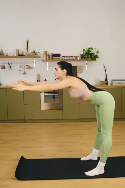 Junge Frau dehnt sich zu Hause und konzentriert sich auf ihr Yoga für das Gleichgewicht. — Stockfoto
